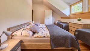 A bedroom with a bed, bedside table, lamp, and a window with a view of greenery. - Lovely apartment for 4 people with WIFI, TV, terrace, pets allowed and panoramic view (Dvur Králové Nad Labem)