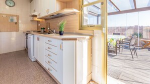 A modern kitchen with white cabinets, a built-in oven, and a window overlooking a deck.