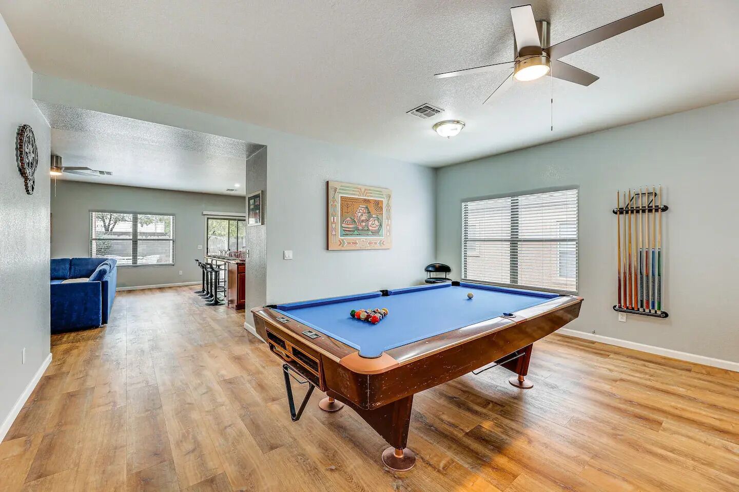 A spacious room with a pool table, a ceiling fan, and a billiards rack.