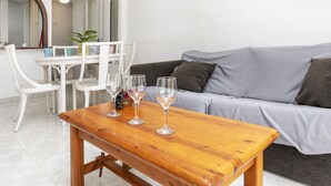 A modern living room with a wooden table, three wine glasses, and a grey sofa. - Cosy apartment for 6 guests with A/C, pool, WIFI, terrace and pets allowed (Salou)