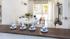 A dining area with a white table, four matching cups, and chairs. - Cosy apartment for 6 guests with A/C, pool, WIFI, terrace and pets allowed (Salou)