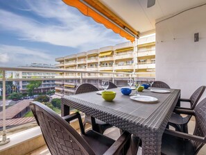 Un balcon avec une table dressée pour le dîner, des chaises et une vue sur un immeuble à plusieurs étages.