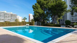 Una piscina rettangolare con superficie d'acqua cristallina e azzurra, circondata da un solarium in legno.