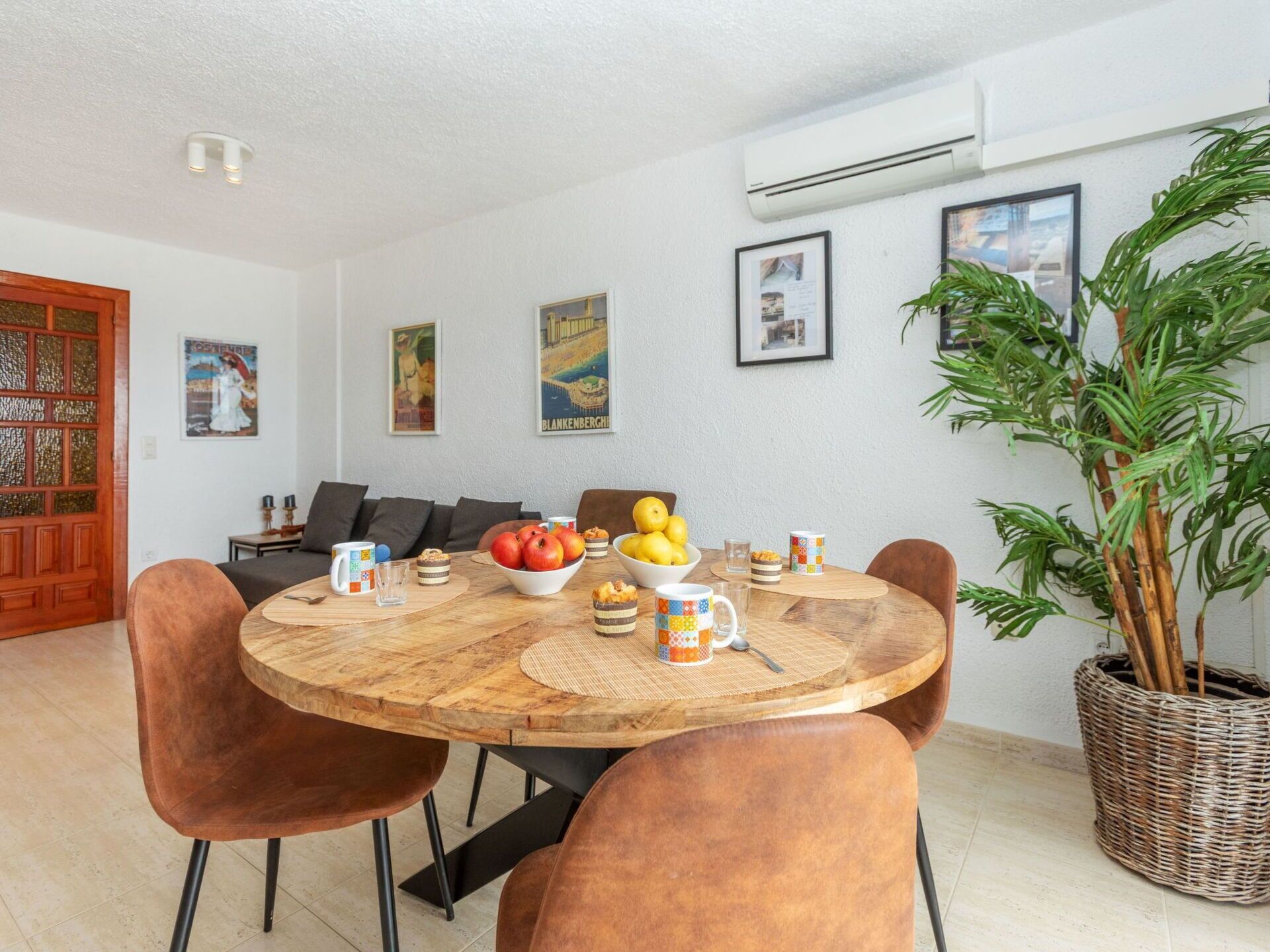 Un coin repas avec une table ronde en bois, des chaises marron et une plante en pot.