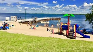 Una playa con un parque infantil, un muelle y una torre de salvavidas.