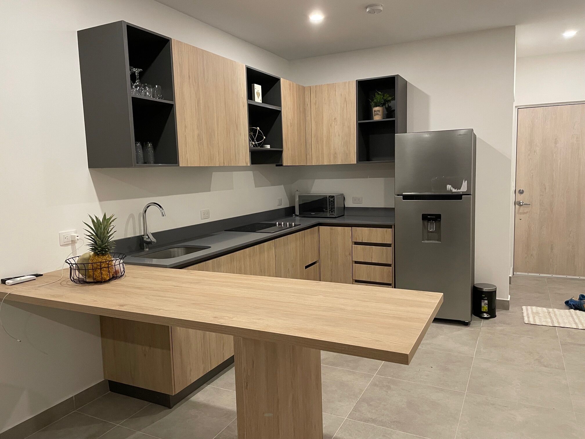 Een moderne keuken met houten kastjes, een roestvrijstalen koelkast, een magnetron en een spoelbak.