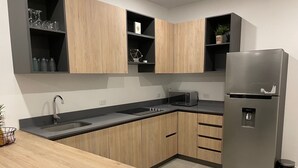 Una cocina moderna con armarios de madera, un refrigerador de acero inoxidable, un microondas y un lavamanos.