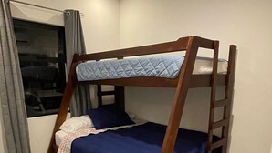 Una cama litera en una habitación con ventana, cortinas y suelo de baldosas.