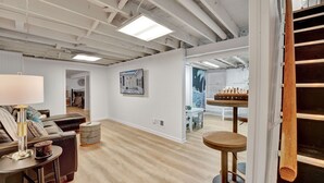 Un intérieur moderne avec un plancher en bois, un canapé, une lampe et une table d’échecs.