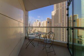 A balcony with a glass door, two chairs, and a small table. - Maison Privee - Stunning JBR Retreat w/ Partial Sea & Marina Views (Dubai)