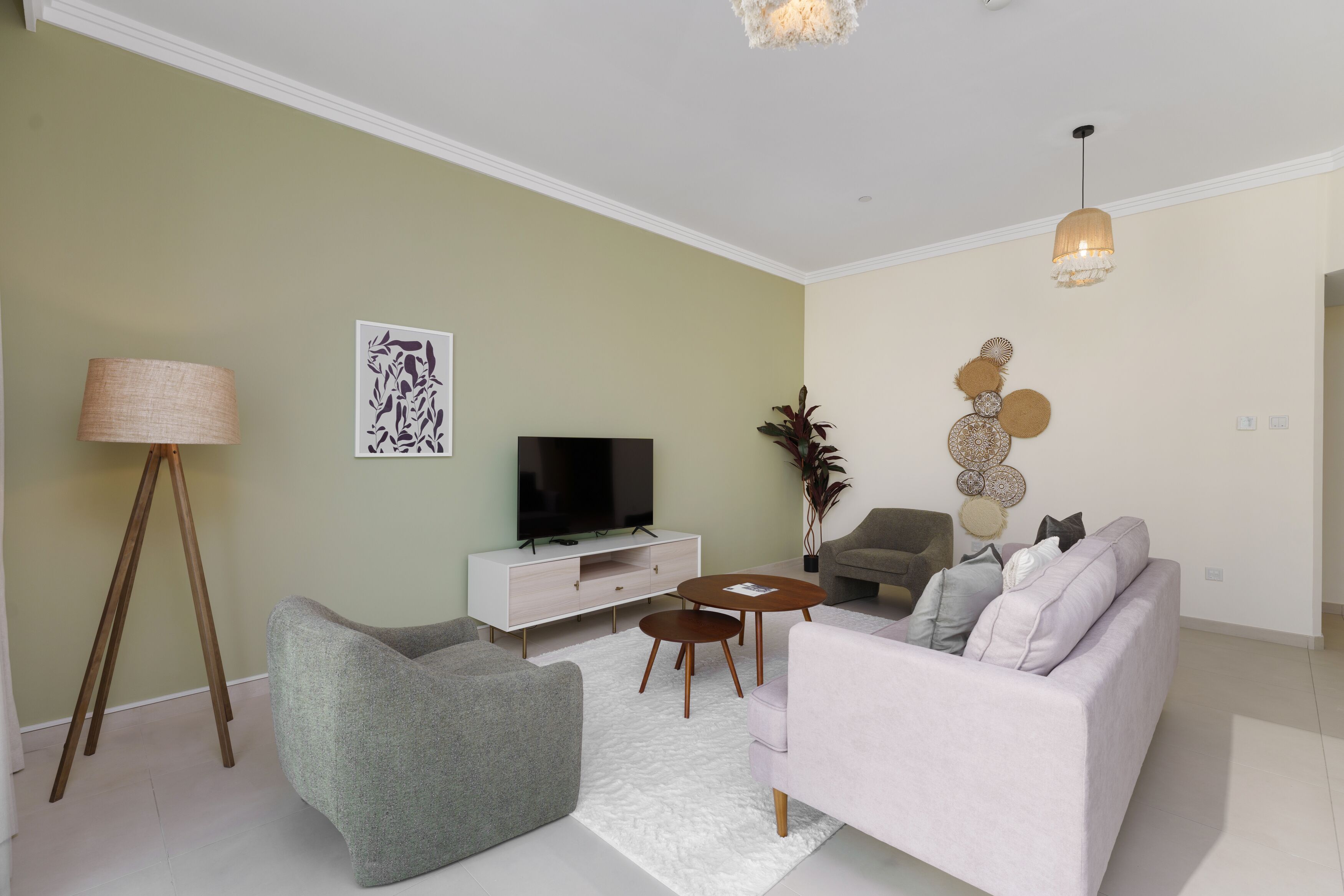 A modern living room with a sofa, armchair, TV, and decorative wall art.