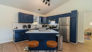 Une cuisine moderne avec des meubles de couleur bleu foncé, des appareils en acier inoxydable et un îlot central doté de tabourets.