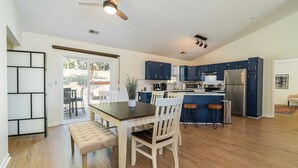 Une cuisine moderne avec des meubles en bois, un îlot central et un coin repas comprenant une table et des chaises.