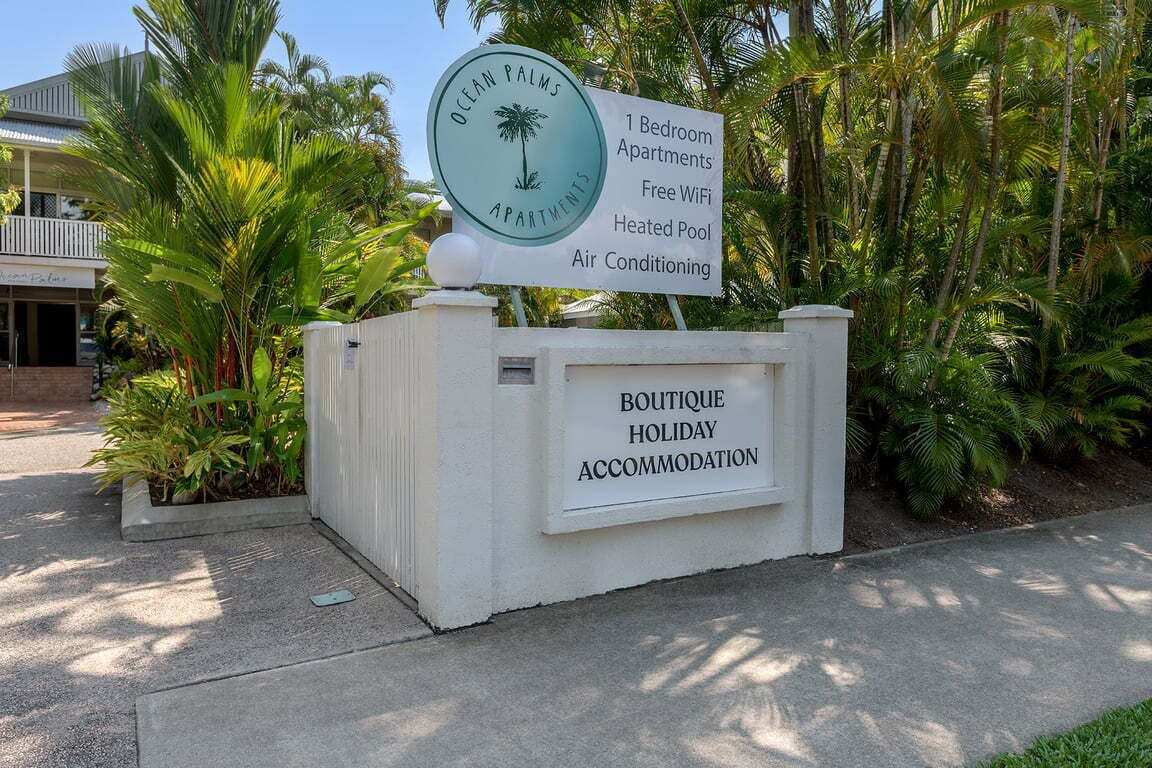 A sign for Ocean Palms Apartments highlighting features like 1 bedroom, free WiFi, heated pool, and air conditioning.