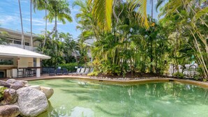Una piscina rodeada de palmeras y un edificio con terraza.