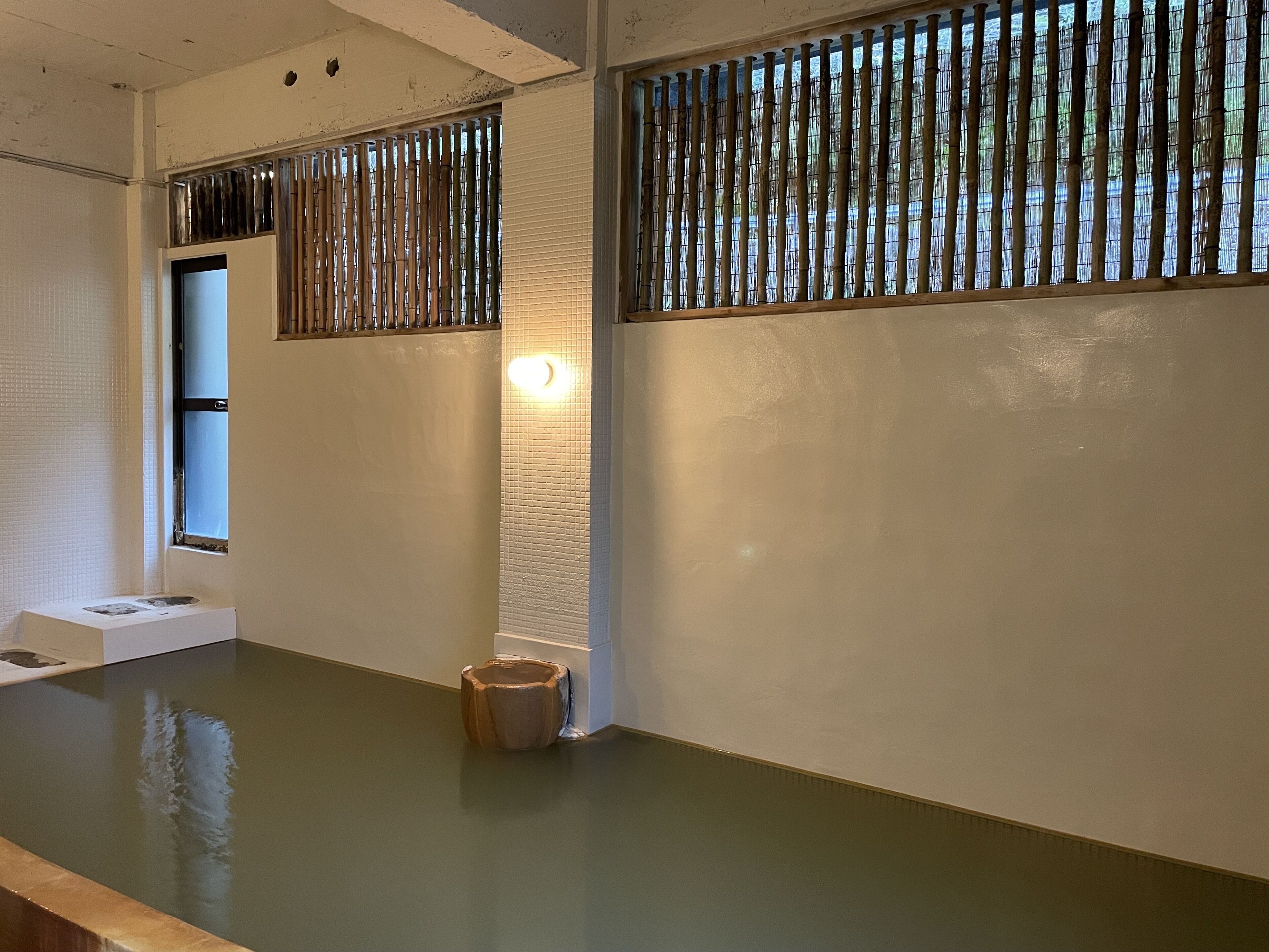 A room with a large window, a wooden floor, and a small table.