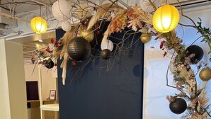 A room with two grey upholstered chairs, a patterned rug, and decorative elements including hanging lanterns and floral arrangements. - yamanoyu (Kirishima)