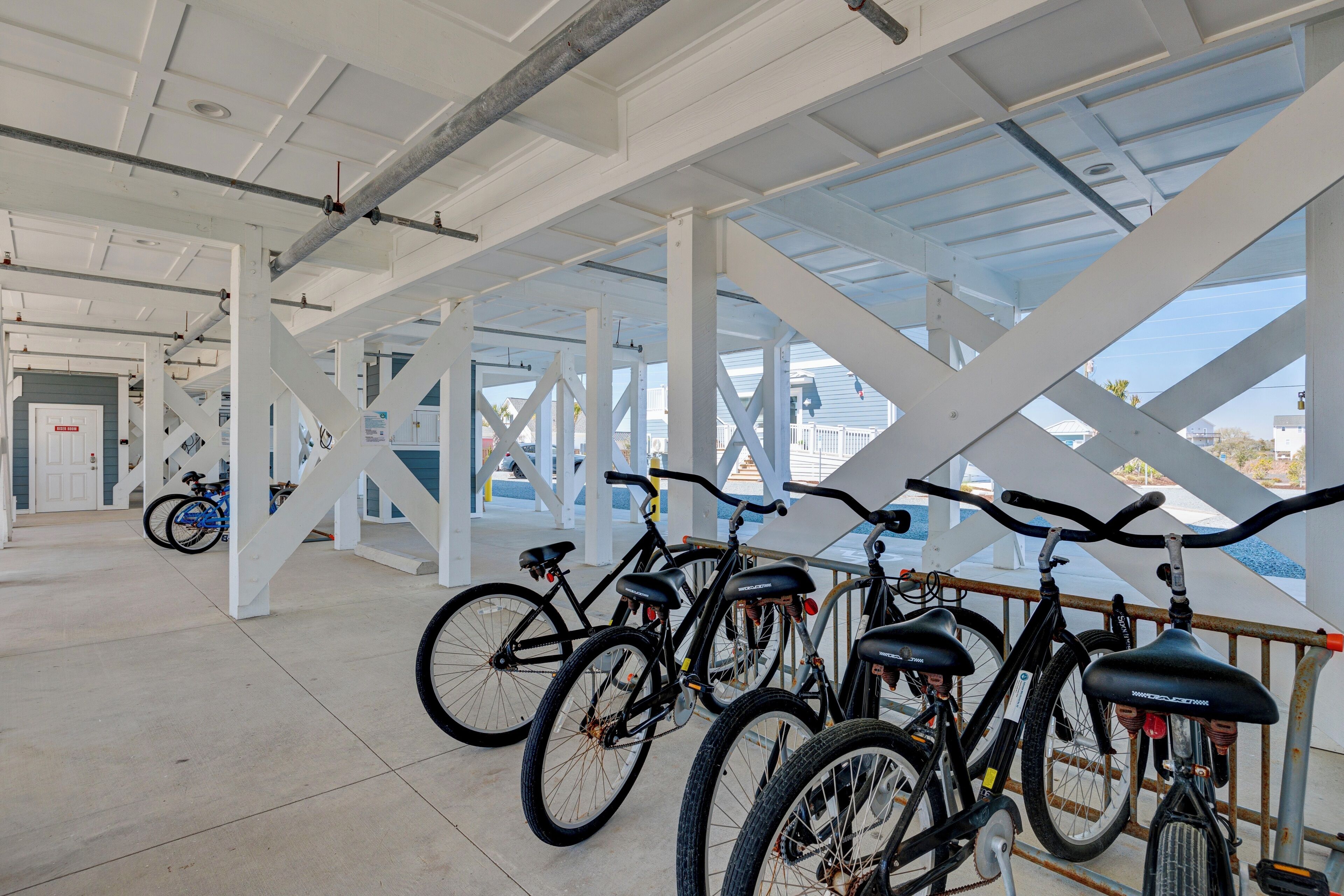Un espacio cubierto para estacionar bicicletas, con bicicletas y una puerta que da a un espacio interior.