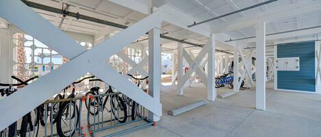 A spacious indoor area with white structural beams and a concrete floor, featuring a bicycle rack with several bicycles.