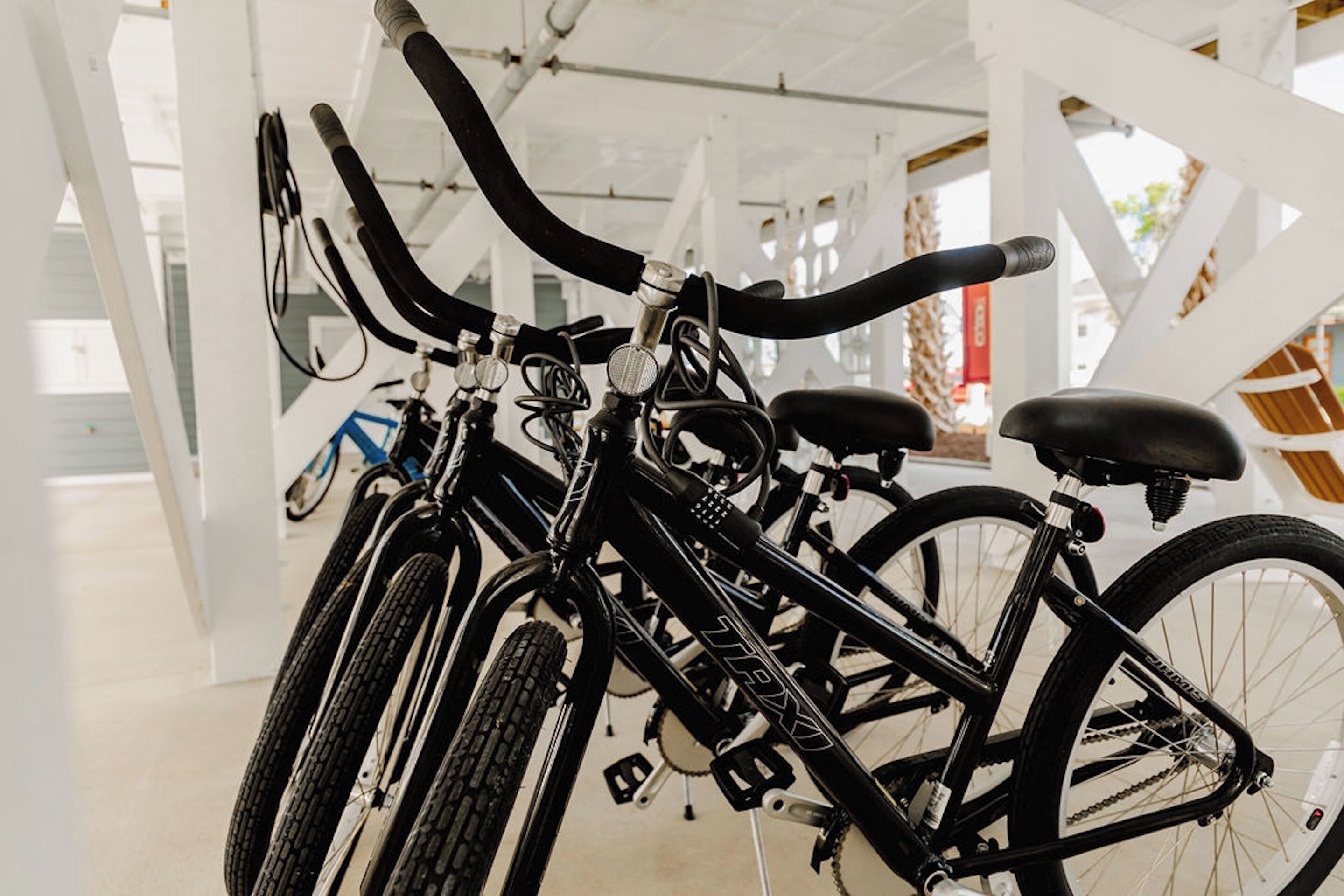 A row of bicycles parked indoors, with a white structure in the background.