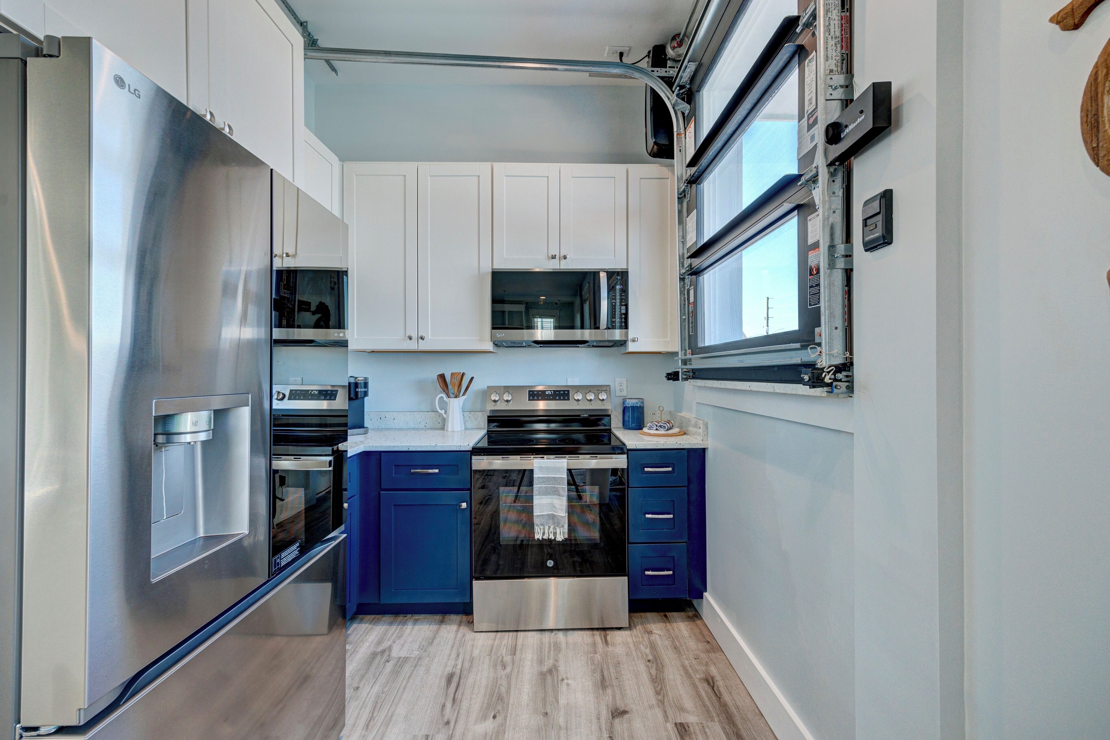 A compact kitchen with stainless steel appliances, blue cabinets, and a microwave.