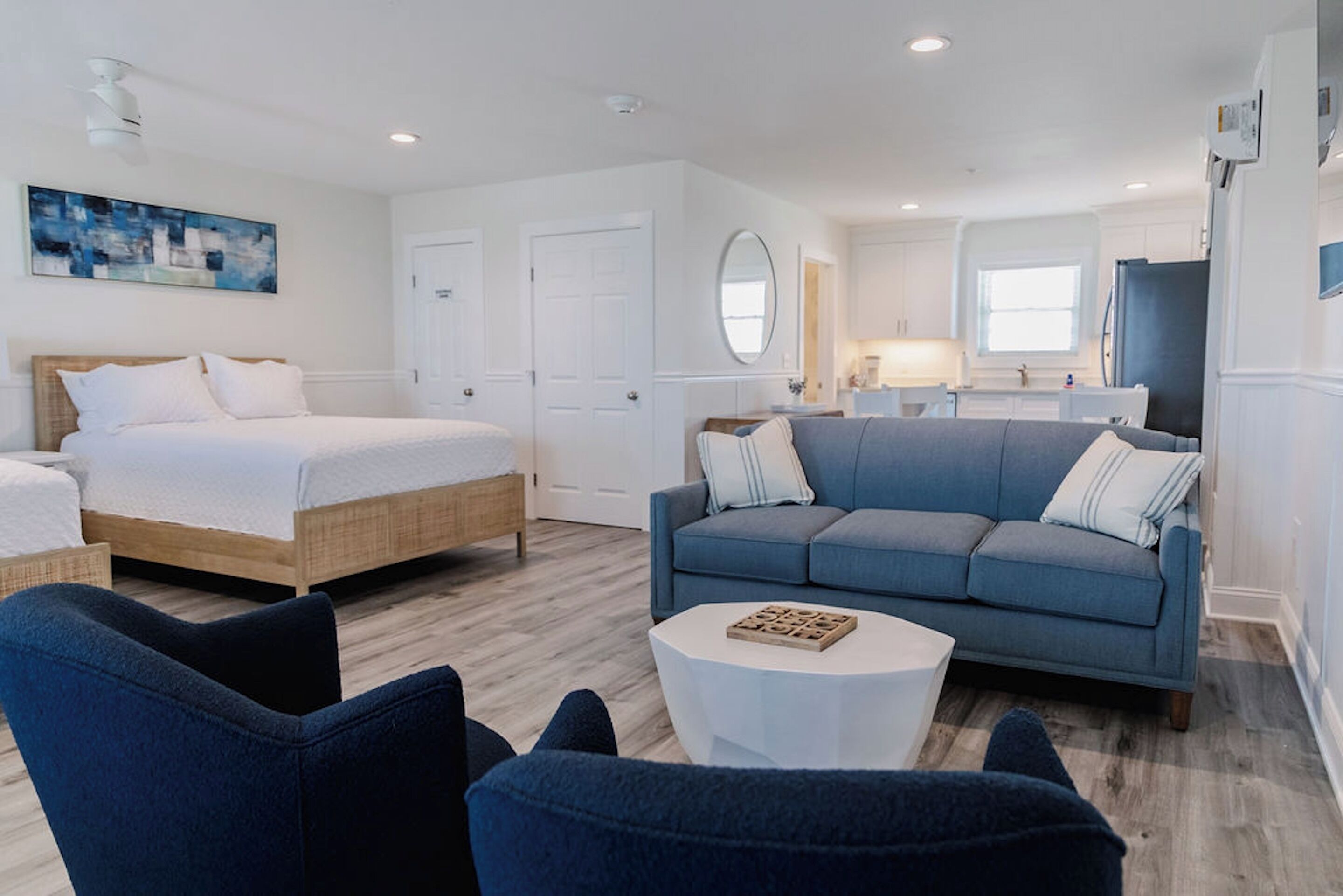 A modern bedroom with a bed, a blue sofa, and a white coffee table.
