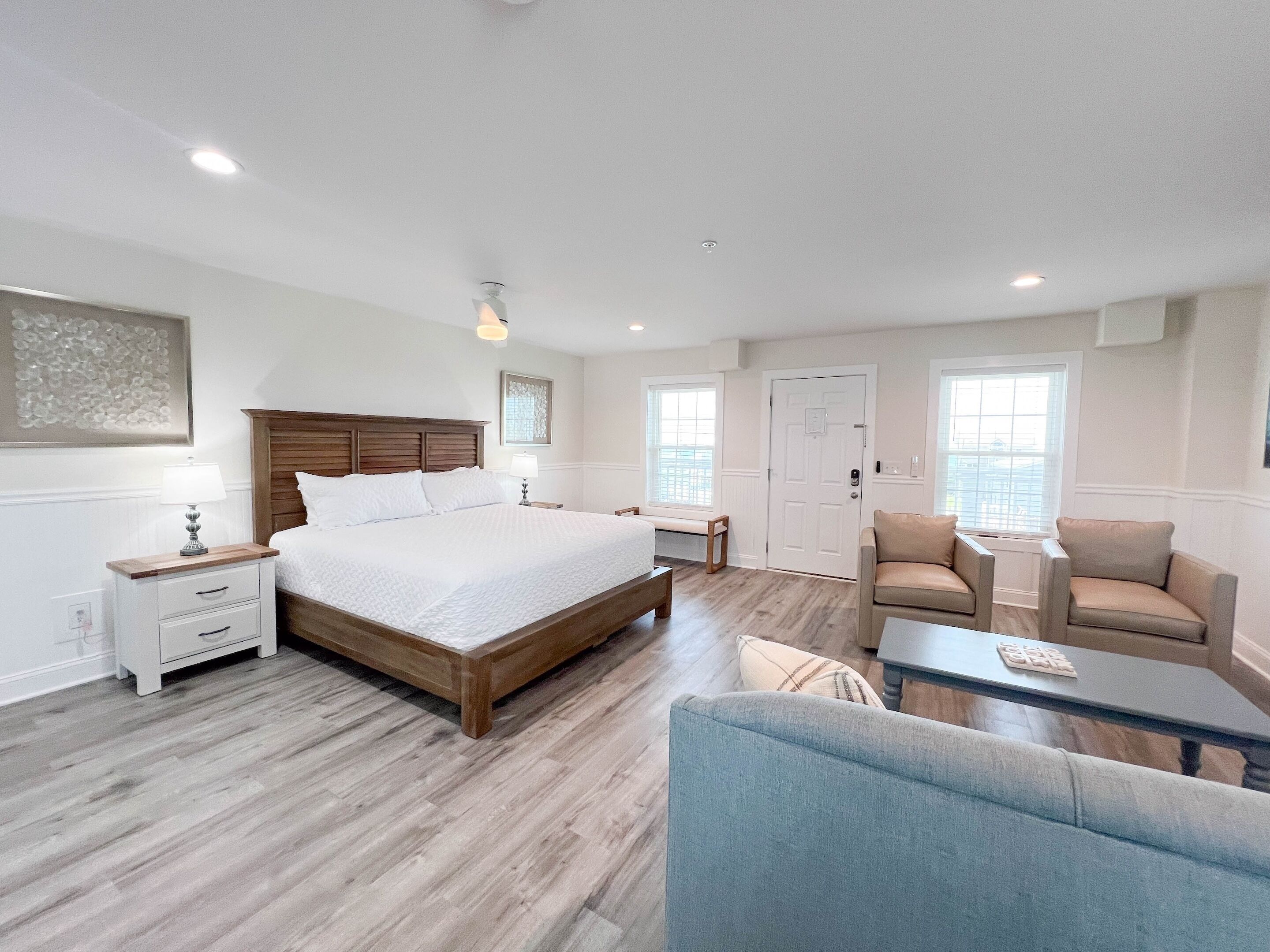 A bedroom with a large bed, bedside tables, a chair, a sofa, and a window.