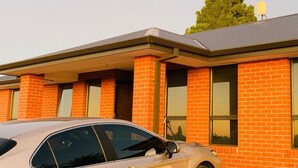 Un edificio con facciata in mattoni, ampie finestre e un'auto parcheggiata davanti.