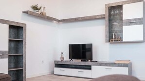 Ein modernes Wohnzimmer mit Flachbildfernseher, integrierten Regalen, einem großen Spiegel und einem minimalistischen Design.