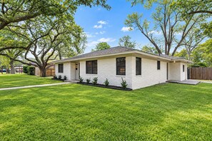 A single-story house with a flat roof, a front porch, and a well-maintained lawn. - Spacious Family Gem: Private Giant Yard | 4br (Baytown)
