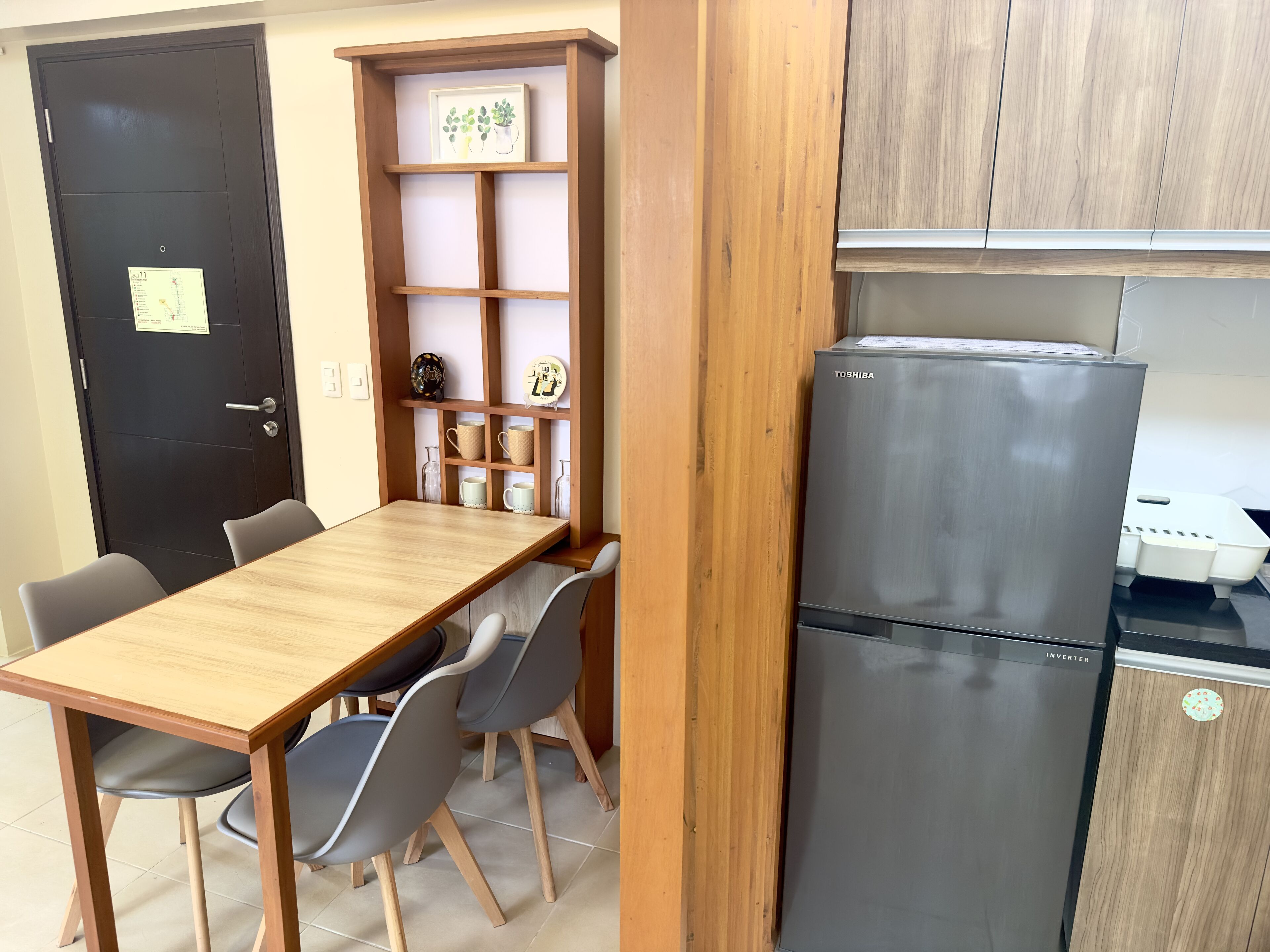A compact kitchen with a stainless steel refrigerator, wooden cabinets, and a small dining area with a table and chairs.