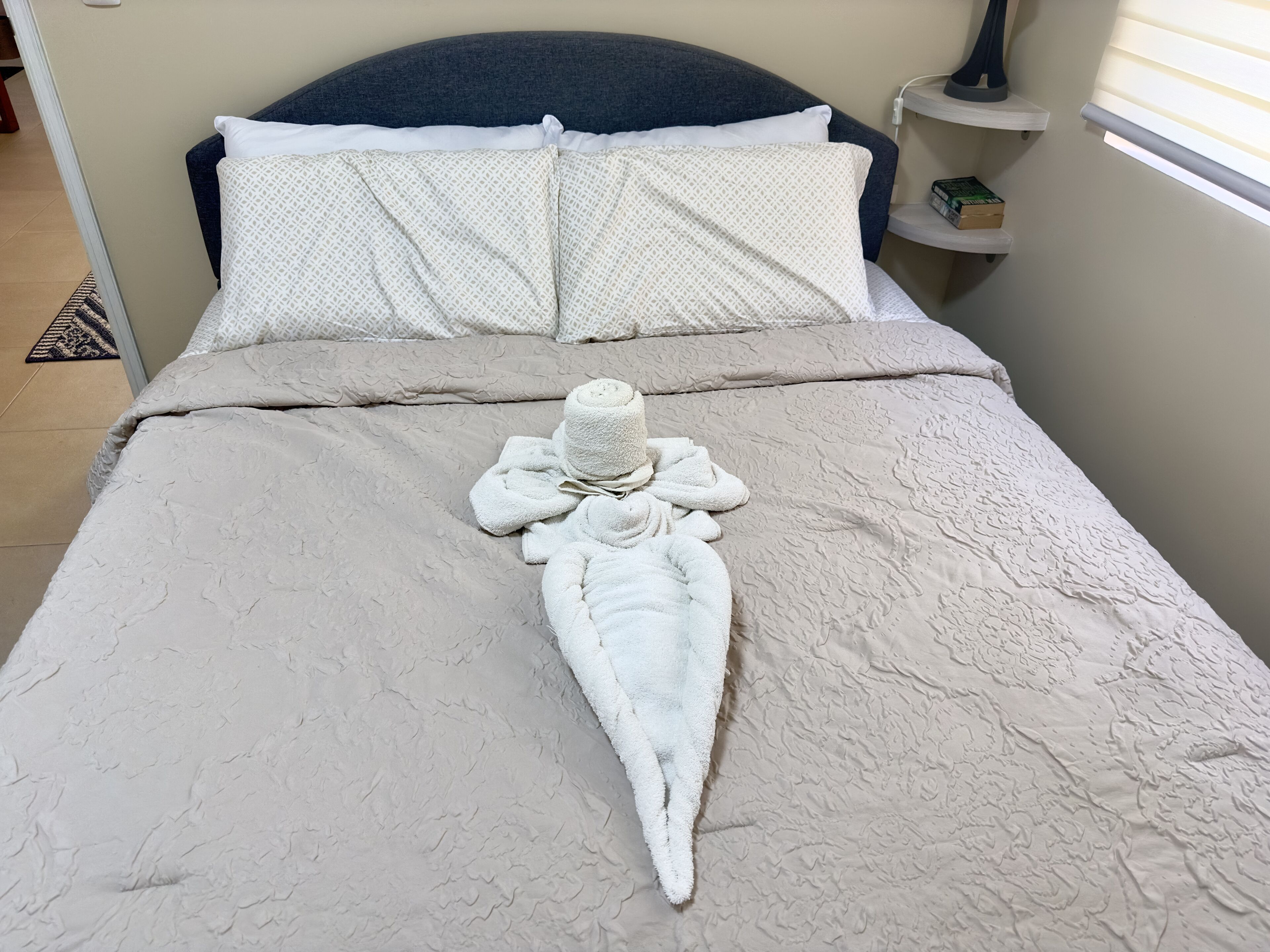 Un lit bien fait, avec une couvre-lit à motifs, des oreillers et une serviette joliment disposée.