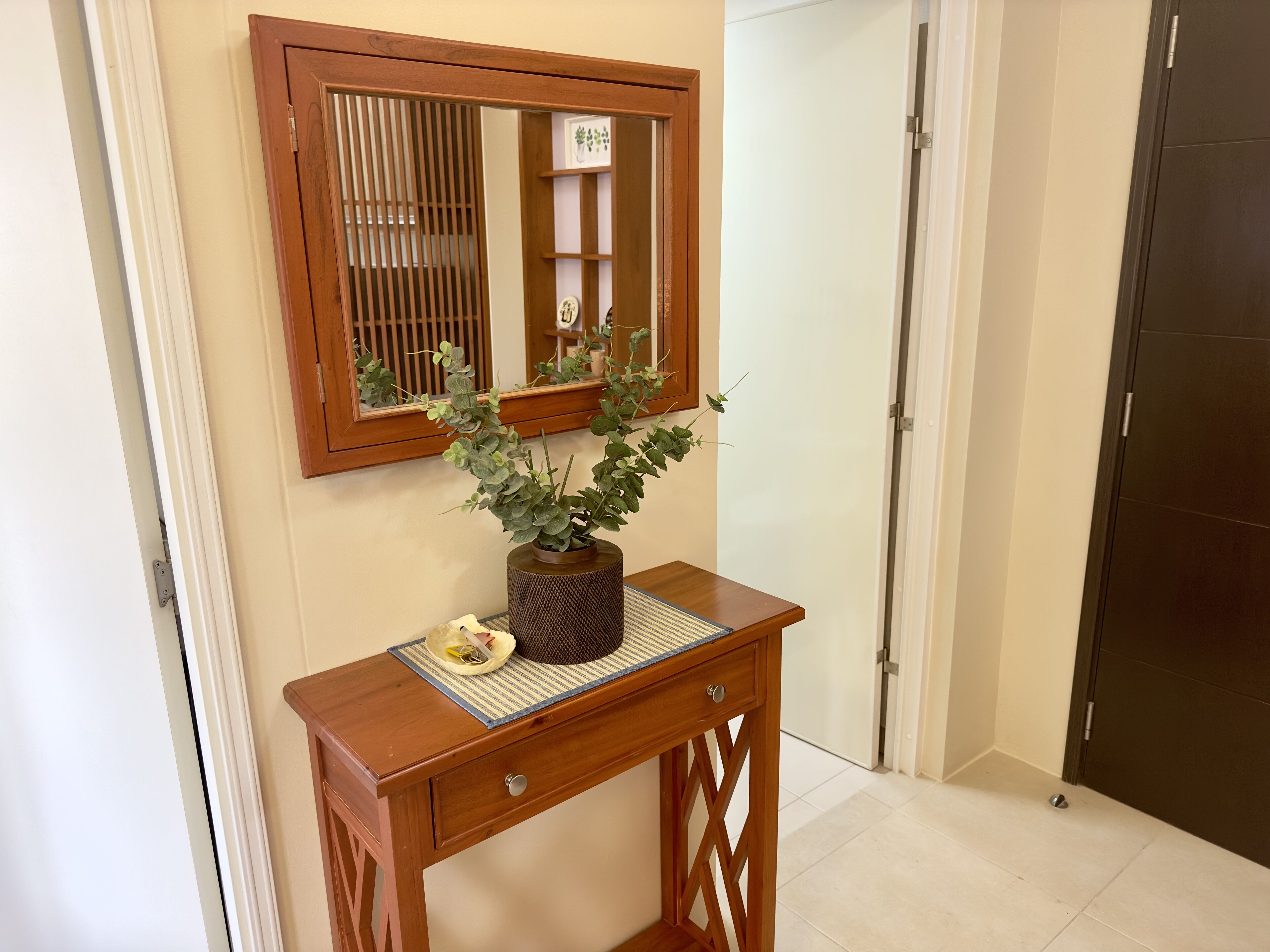 A wooden console table with a potted plant, a mirror, and a small decorative plate.