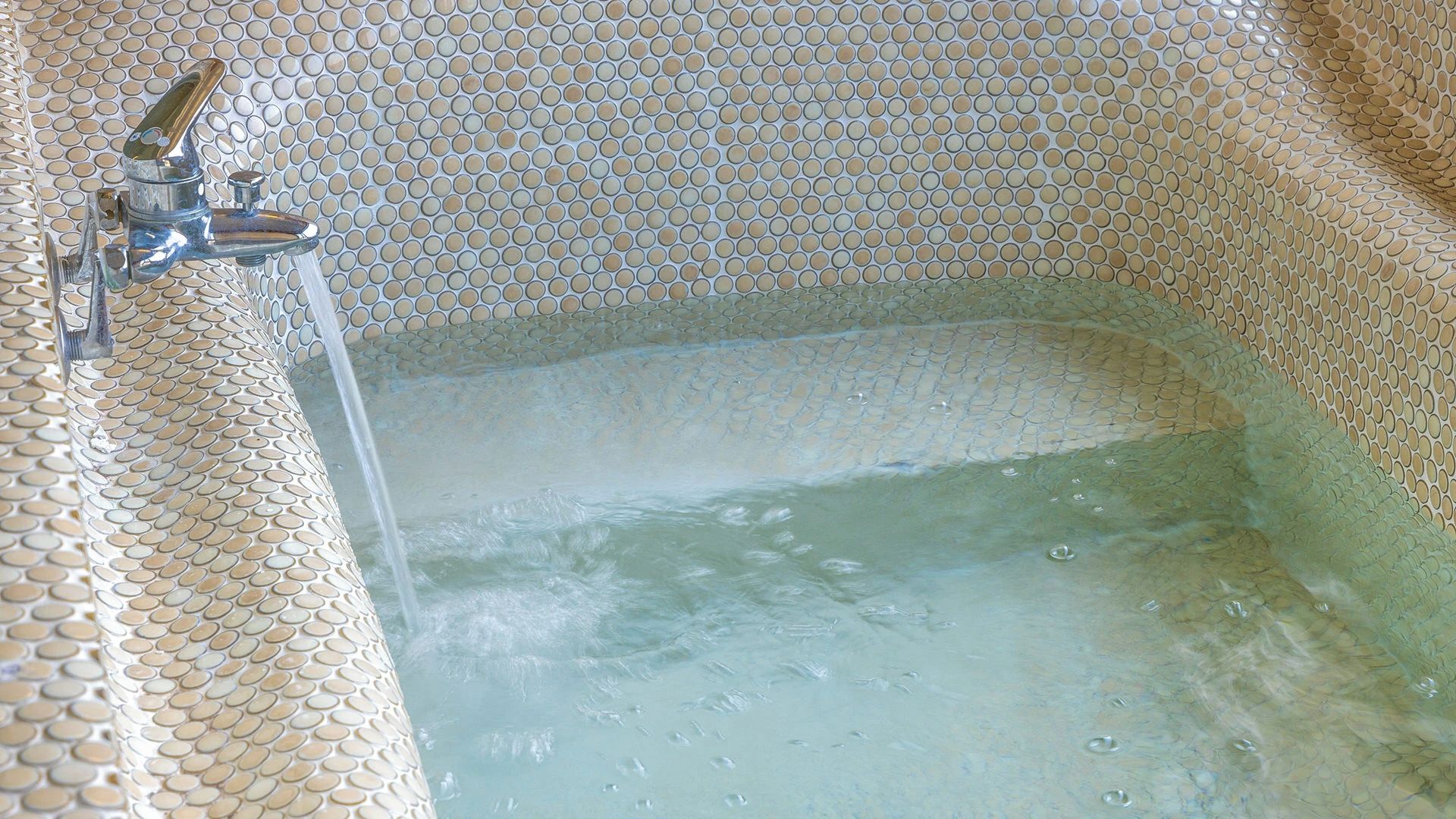 Une baignoire avec un mur texturé et un robinet.