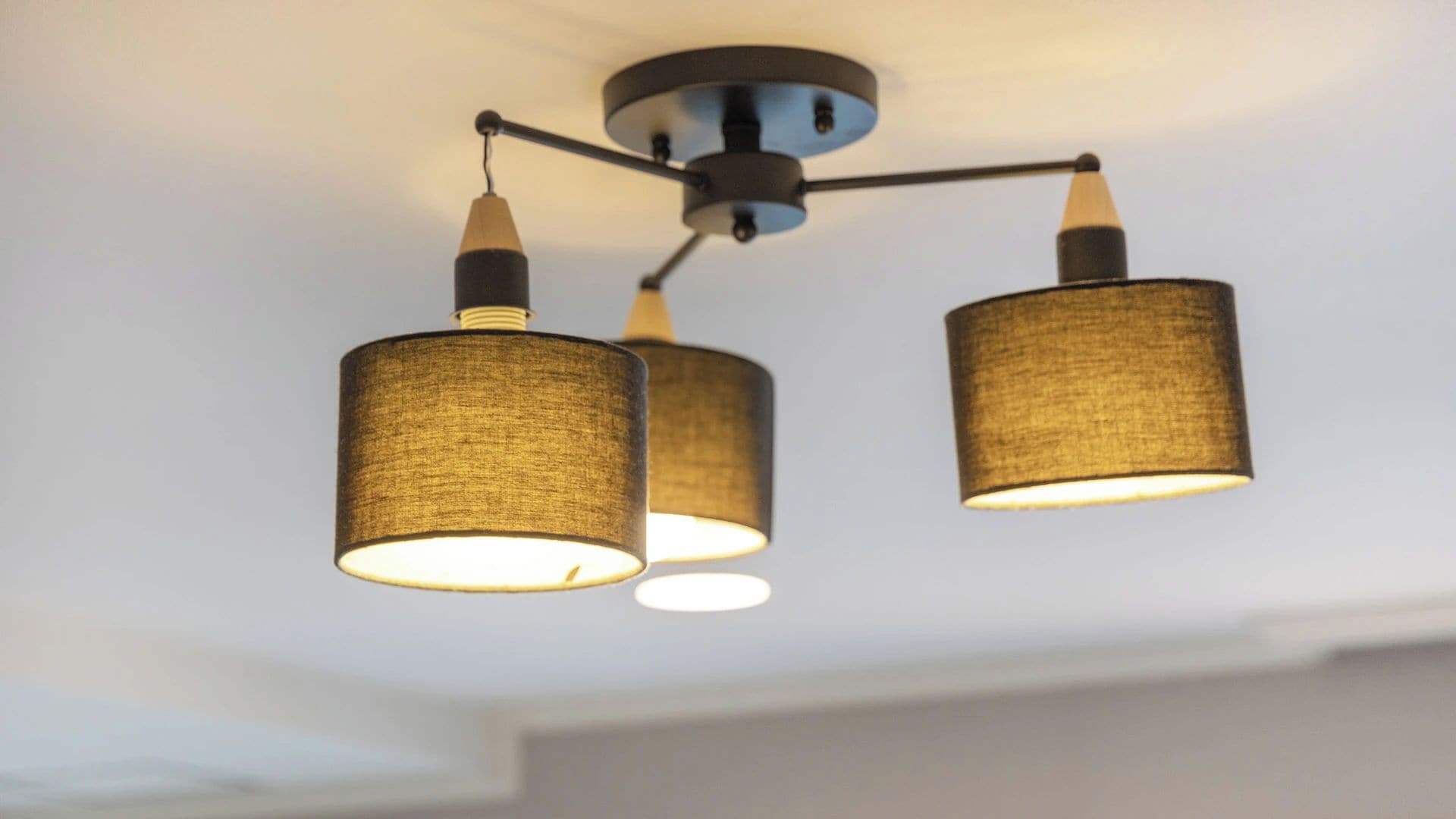 A ceiling light fixture with three cylindrical shades.