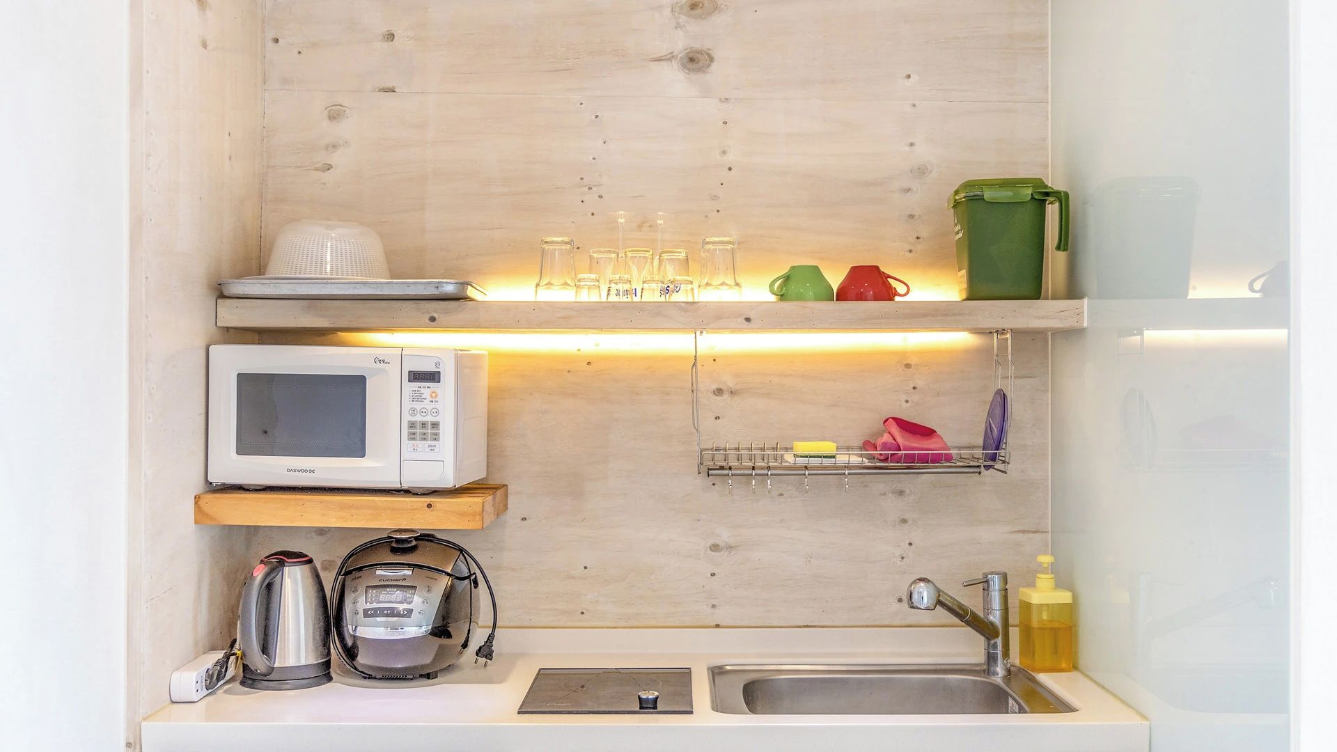 Cozinha compacta com micro-ondas, chaleira e chaleira no balcão.