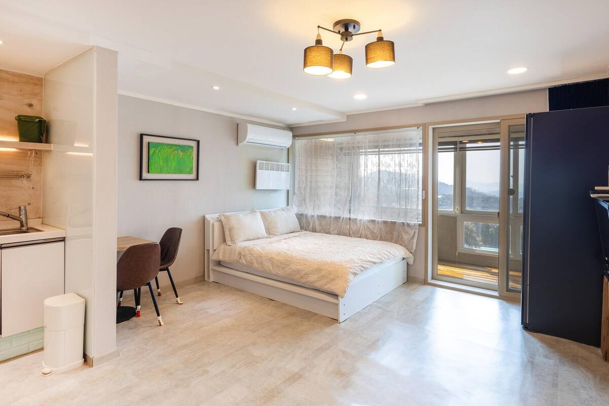 Ein modernes Schlafzimmer mit Bett, Schreibtisch und Fenster.