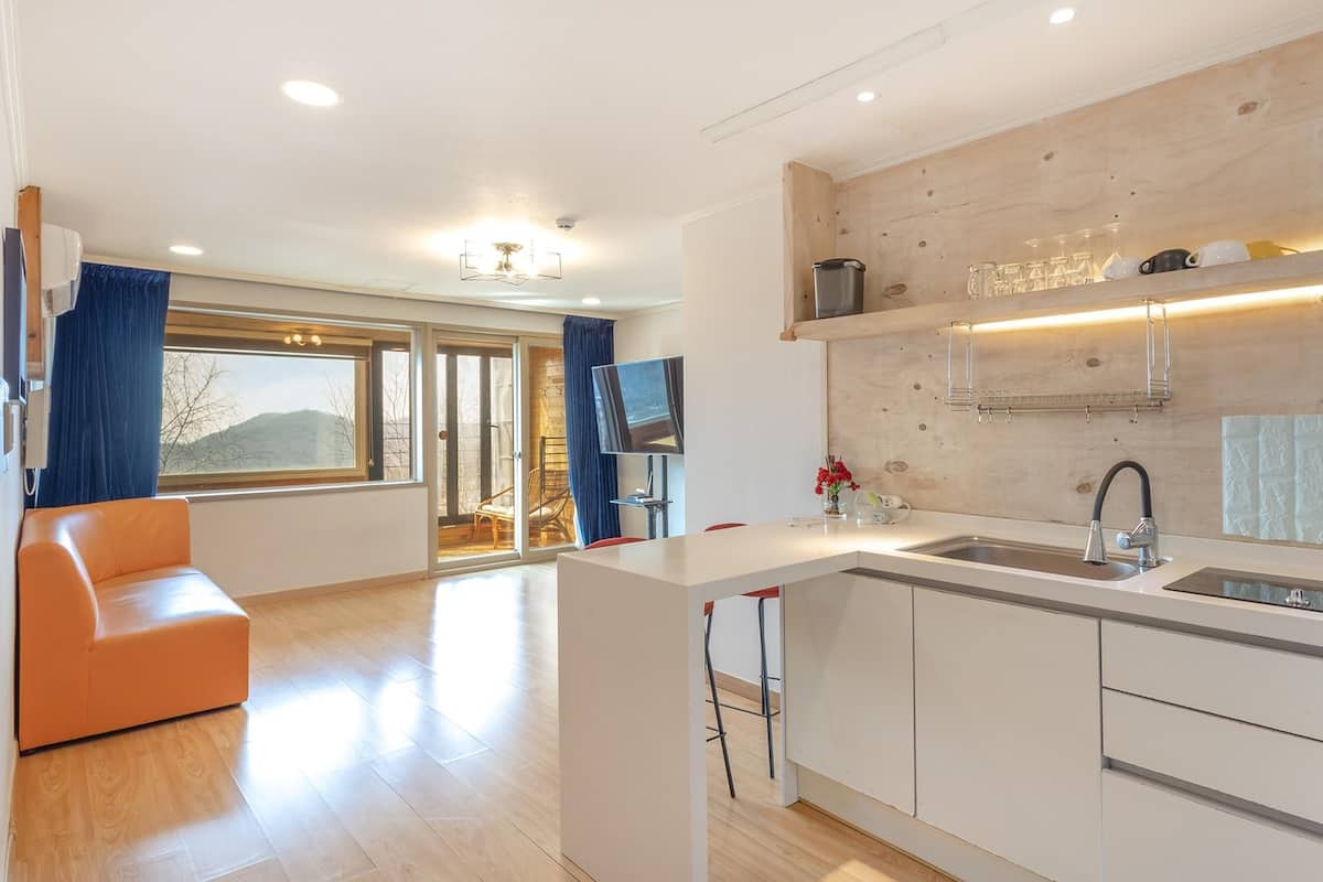 Eine moderne Küche mit einer großen Kochinsel, einem Essbereich mit einer Couch und Blick ins Freie.
