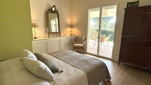 Ein Schlafzimmer mit Bett, Schminktisch, Stuhl und einer Schiebetür zu einem Außenbereich.