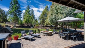 Une terrasse extérieure équipée d’un barbecue, de chaises longues, d’un foyer et d’une table avec des chaises.