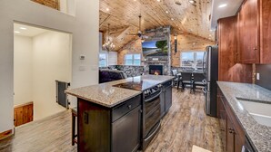 Una cocina amplia con una isla central, techo de madera y una pared de acento de piedra.