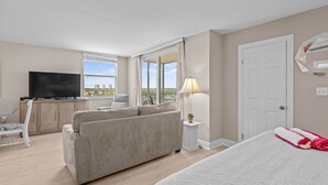 Ein Hotelzimmer mit Bett, Sofa, Fernseher, Schreibtisch und einem Fenster mit Blick.