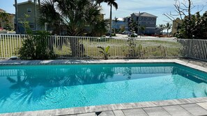 A rectangular swimming pool with a white fence surrounding it.