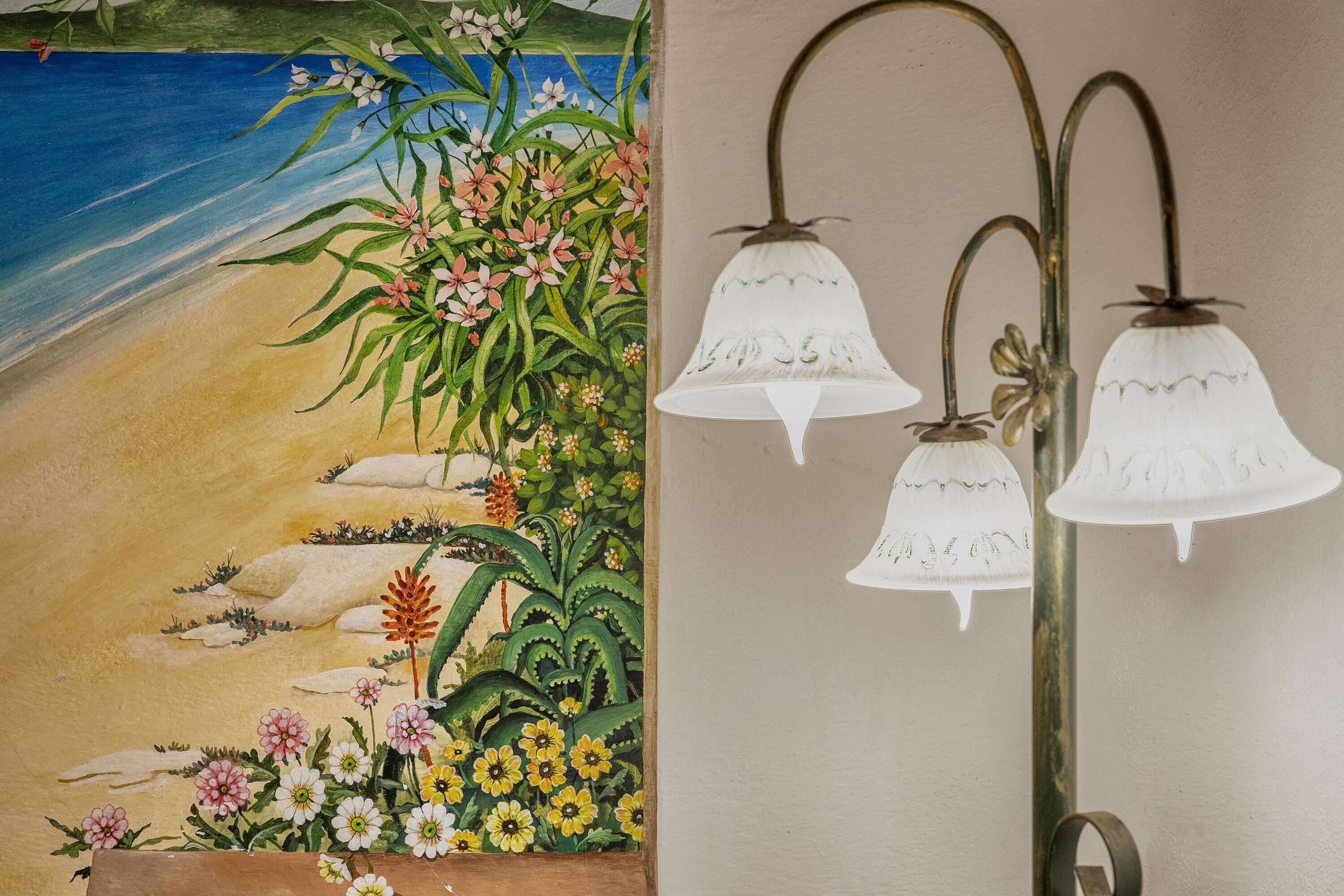 A wall with a beach mural and three wall-mounted light fixtures.