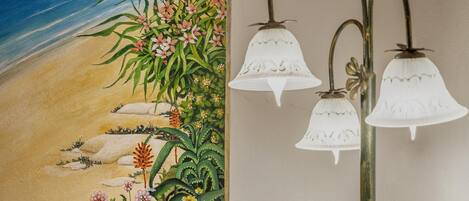 A wall with a beach mural and three wall-mounted light fixtures.