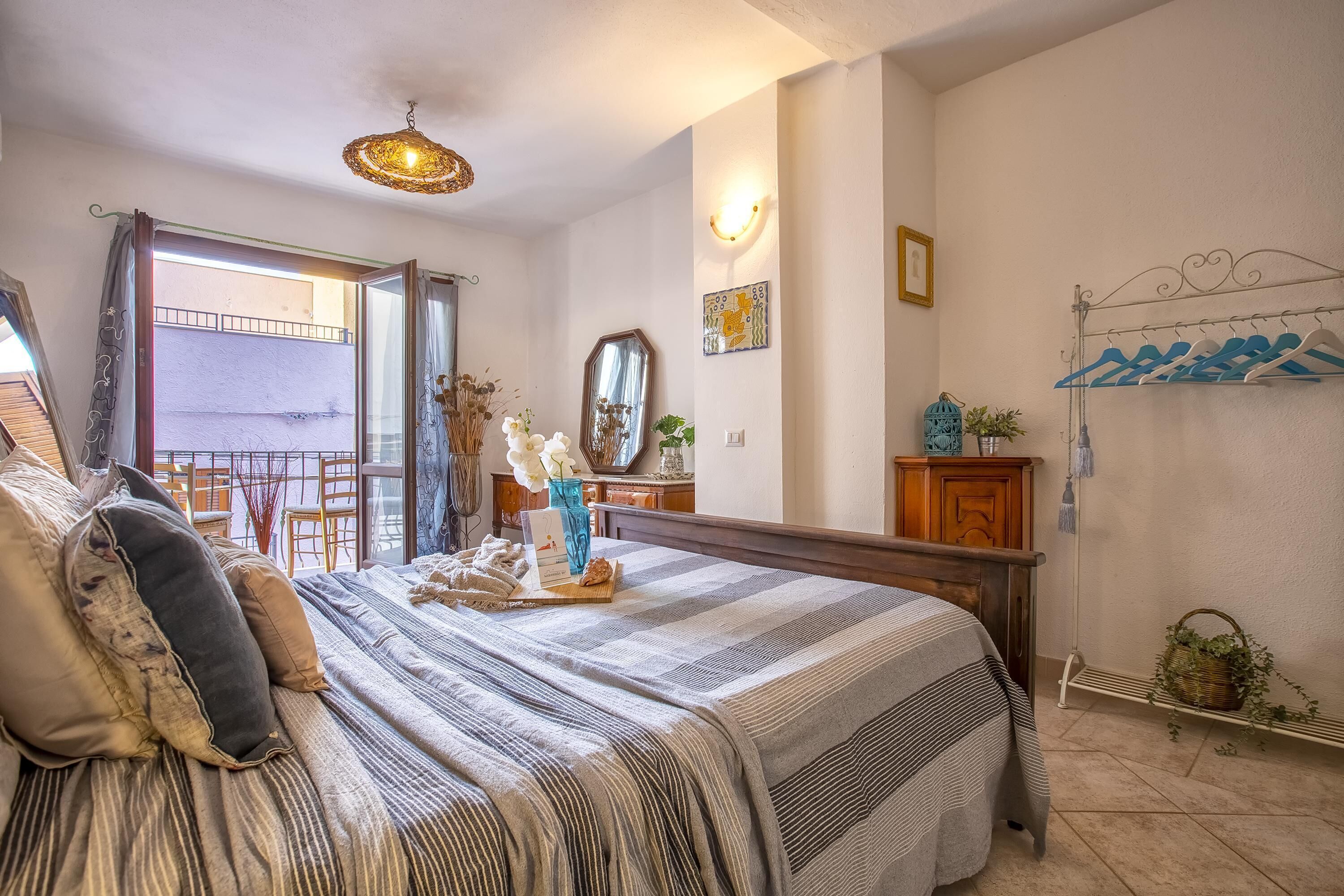 Un dormitorio con una cama grande, un aparador de madera, un espejo y vistas al balcón.
