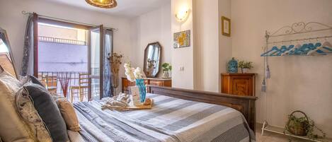 Un dormitorio con una cama grande, un aparador de madera, un espejo y vistas al balcón.