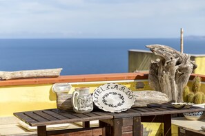 A wooden table with a decorative plate, a ceramic pitcher, and a rustic wooden sculpture. - Sardinia Re - Casa Bellavista Panoramic View (Castelsardo)