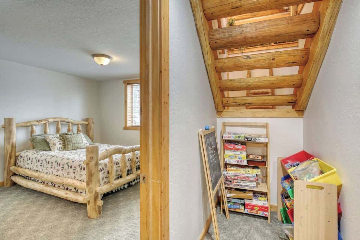 A bedroom with a wooden bed, a sloped ceiling, a bookshelf, and a small desk.