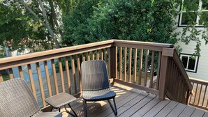 Eine Holzterrasse mit zwei Korbstühlen und einem kleinen Tisch.